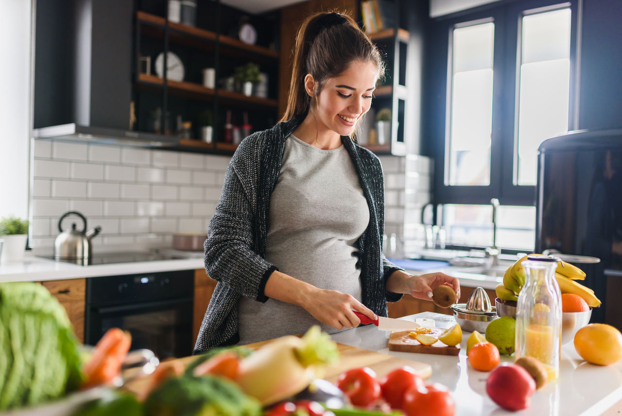 Young beautiful pregnant woman preparing healthy meal with fruites and vegetables